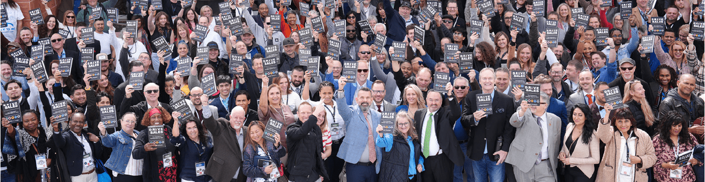 A large group of entrepreneurs holding the D.R.I.V.E. book.